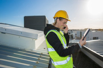 female worker on construction site using tablet pc and mobile phone