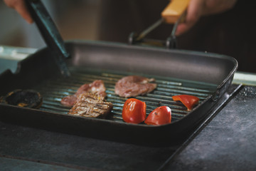 chef is frying meat and vegetables in a pan