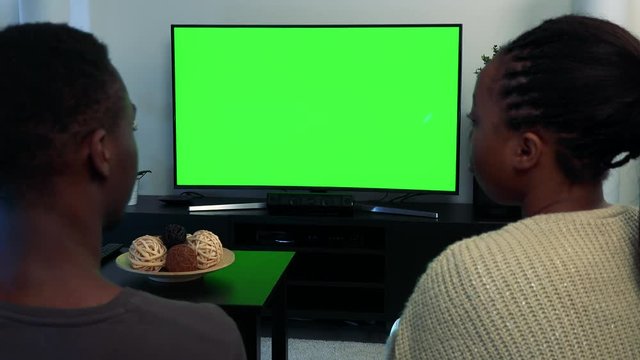 Young black couple watch television in living room - green screen - closeup