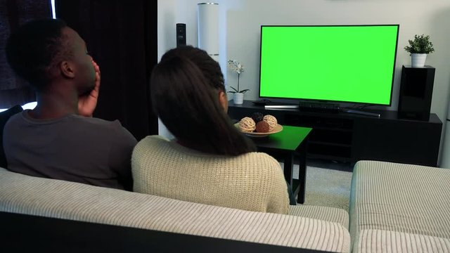 Young black unhappy couple watch television in living room and they are angry 