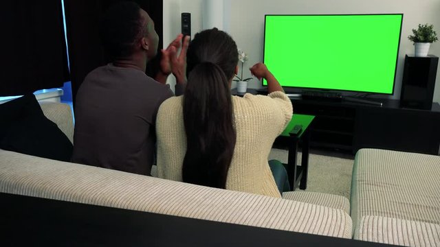 Young black couple watch television in living room and they support someone