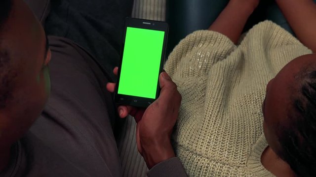 Young black couple work on smartphone in living room - shot from above - closeup