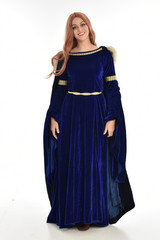 Naklejka premium full length portrait of girl wearing long blue velvet gown and fur lined cloak, standing pose on white background.
