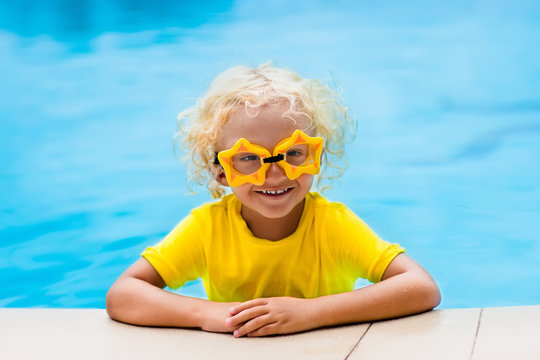 Child with goggles in swimming pool. Kids swim.