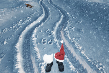 Stiefel mit Weihnachtsmütze auf verschneiter Strasse mit Schneespuren