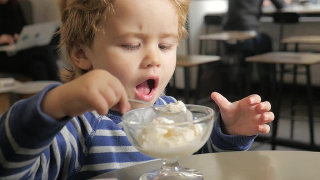 Ice cream for child. Сheerful boy opens and closes his eyes. Sweet dairy products. Healthy natural food for children