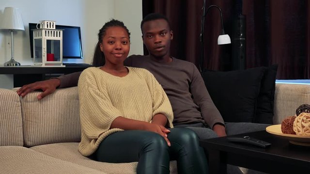 Young black happy couple talk to camera together in living room 
