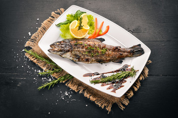 Fish Trout baked with vegetables and spices. On a wooden background. Top view. Free space for text.