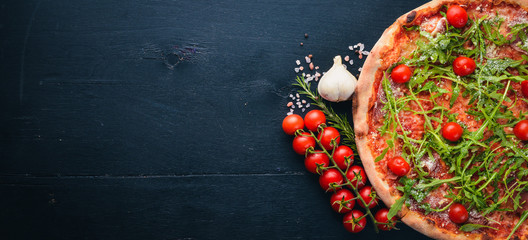 Fototapety  Pizza Primavera. Pomidory koktajlowe, rukola, ser. Na drewnianym tle. Widok z góry.