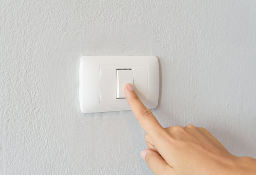 Close up of woman finger  turning on light switch with white background copy space.