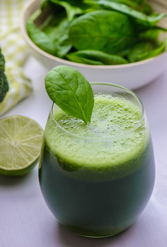 Healthy naturally green freshly squeezed juice of vegetables on the white wood table.