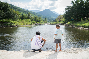 Fototapeta na wymiar Dad and son feeding fish at river