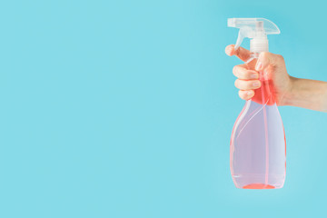 cropped view of hand holding spray bottle, isolated on blue
