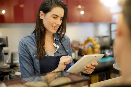 Waitress in coffee shop taking order on digital tablet