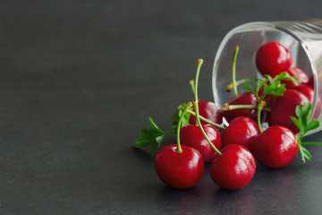 Close up fresh cherries on black granite table in side view with copy space for background or wallpaper. Cherry have high vitamin C and have sweet and sour taste. Healthy fruits concept.