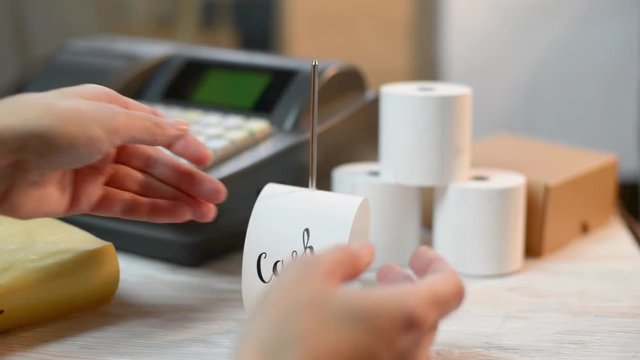Woman working with Electronic Cash Register and bill stick holder
