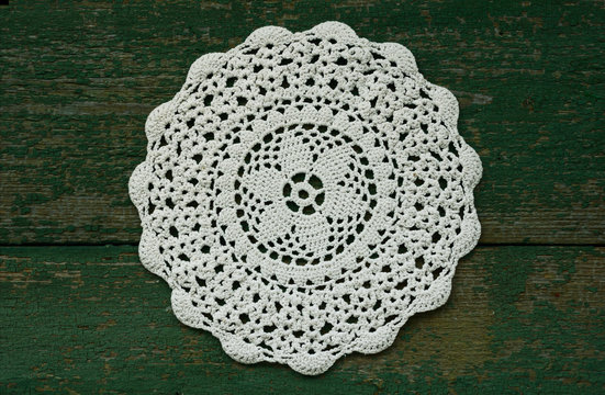 Snowflake like vintage crocheted lace napkin with wooden green background