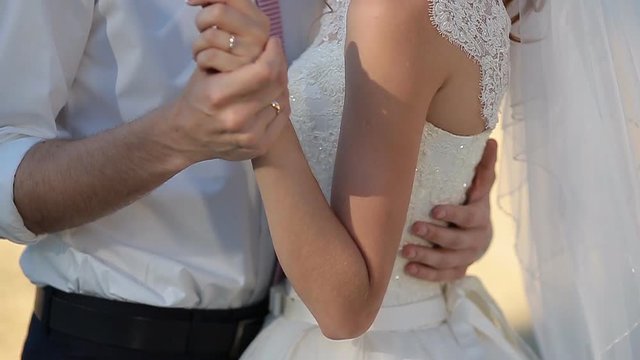 A Romantic Bride and Groom Couple Holding Hands on Wedding Day at Sunset. In 4k.
