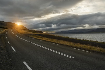 a deserted asphalt road running away into the hills. Iceland. The spirit of travel and adventure.
