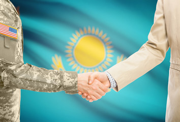 USA military man in uniform and civil man in suit shaking hands with adequate national flag on background - Kazakhstan