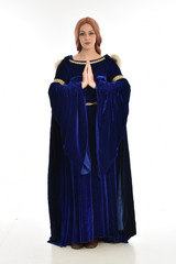 full length portrait of girl wearing long blue velvet gown and fur lined cloak, standing pose  on white background.