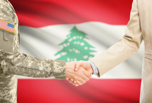 USA military man in uniform and civil man in suit shaking hands with adequate national flag on background - Lebanon