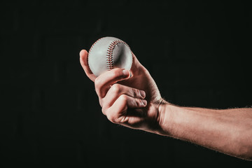 close-up partial view of male hand holding baseball ball isolated on black