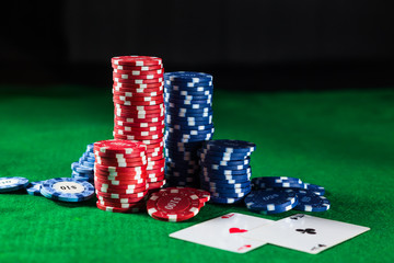 Poker chips with two cards aces on a green table on a black background