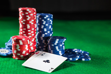 Poker chips with two cards aces on a green table on a black background