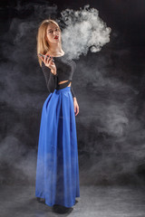 Beautiful girl vaping from e-cigarette on a black background