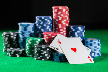 poker chips stack with two cards an ACE. On the green table on a black, dark background.