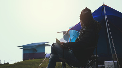Asian man travel relax in the holiday. camping on the Mountain. sit read a book on the chair. Thailand