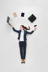 overhead view of businesswoman with various office supplies using laptop isolated on grey