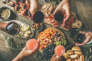 Foto op Plexiglas Plat leggen van vrienden die samen eten en drinken. Bovenaanzicht van mensen die feesten, verzamelen, dineren samen aan een houten rustieke tafel met wijnsnacks en fingerfoods. Handen met bril © sonyakamoz