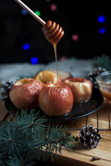 baked apples for the new year, fir-tree, cones, honey New Year's lights on a black background