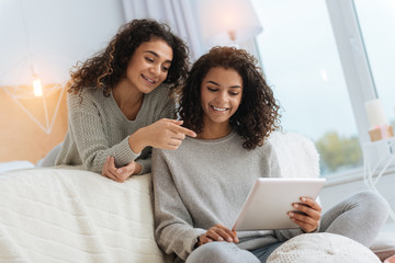 What is that. Happy young ladies smiling cheerfully and focusing their attention on a screen of a...