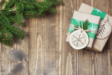 Christmas gift box in rustic style wrapped in paper with decor of wooden sliced with woodburning symbol.