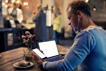 Man using tech gadgets in cafe