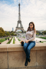 Beautiful girl posing to the photographer against the background of the Eiffel Tower. Autumn...