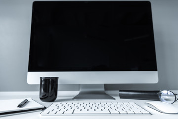 working place with computer, black cup and notebook