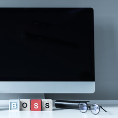 computer and wooden cubes with word Boss on a table