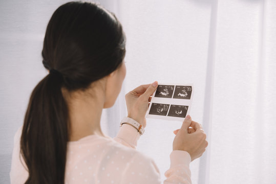 pregnant woman looking at photo of ultrasound diagnostics