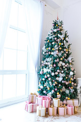 Christmas living room with a Christmas tree, gifts and a large window. Beautiful New Year decorated classic home interior