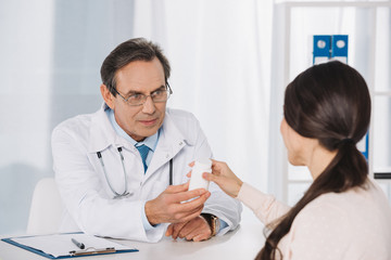 male doctor giving pills to female patient