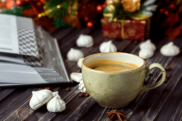 A cup of coffee with meringues and a book on a wooden background, new year's decor