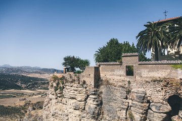 scenic view of stone wall, palms and building on rock against mountains landscape, Ronda, spain