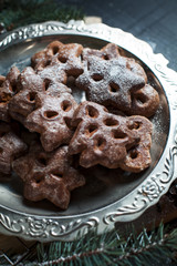 gingerbread cookies for the new year and Christmas on a silver tray, Christmas tree, cones, cinnamon on a wooden cutting board on a dark background