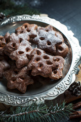 gingerbread cookies for the new year and Christmas on a silver tray, Christmas tree, cones, cinnamon on a wooden cutting board on a dark background
