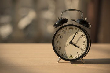 black alarm clock on wood table at morning.