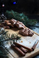 gingerbread cookies for the new year and Christmas, Christmas tree, cones, cinnamon on a wooden cutting board on a dark background